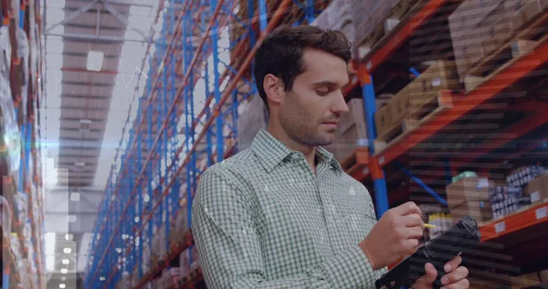 Kareli gömlek giyen bir depo çalışanı koridorda barkod tarayıcı ve raflarla kutuları tarıyor. Sanayi, lojistik, organizasyon, verimlilik, üretkenlik, altyapı, işlemler