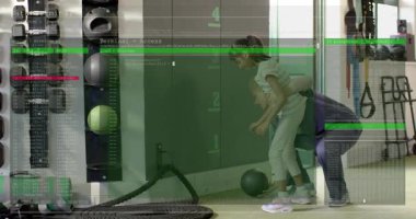 Spor salonunda top için çömelen öğrencilere rehberlik eden antrenör yeşil kaplamaların yükselmesine ve sonra geri çekilmesine neden oluyor. Fitness, eğitim, egzersiz, gençlik, rehberlik, teknoloji, dijital