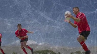 Kırmızı oyuncu, ragbi sahasında ilerliyor. Mavi rakip hücum ederken ileri hücum ediyor. Atletizm, takım çalışması, spor, rekabet, hareket, açık hava, hareketli