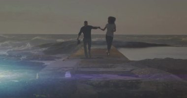 Deniz kenarındaki kayalıklarda yürüyen Afro-Amerikan çifte karşı ışık animasyonu. Aşk ve ilişki kavramı