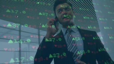 Ofiste akıllı telefondan konuşan beyaz iş adamına karşı borsa veri işleme. küresel finans ve iş teknolojisi kavramı