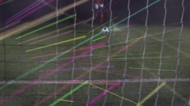 Futbolcu öne çıkıp penaltı atmak için topa vuruyor. Ağ, neon çizgilerle şişiyor. Atletik, spor, hareket, dijital, gece, rekabet, yoğunluk