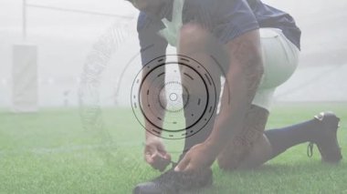 Erkek futbolcu sahada krampon bağcıklarını bağlarken HUD spor ölçümlerinde zayıflıyor. Sporcu, antrenman, teknoloji, dayanıklılık, fitness, performans, stadyum