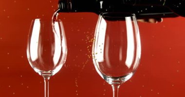 Kırmızı arkaplanda bardaklara dökülen kırmızı şarap üzerinde hareket eden sarı noktaların animasyonu. kış, noel ve gelenek konsepti dijital olarak oluşturulmuş video.