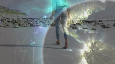 Sahilde yürüyen bir kadın dijital küreyi yoğunlaştırıyor ve teknolojik bağlantıyı gösteriyor. Sahil şeridi, teknoloji, bağlantı, yenilikçi, dingin, gelecekçilik, doğa