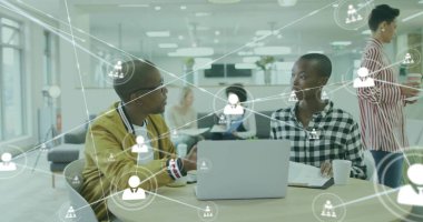 Dizüstü bilgisayarı inceleyen işbirlikçi profesyoneller, açık ofiste ağ simgeleriyle dokümanlar. Eş çalışma, takım çalışması, dijital bağlantı, modern ofis, profesyonel işbirliği, açık çalışma alanı, işyeri ortamı