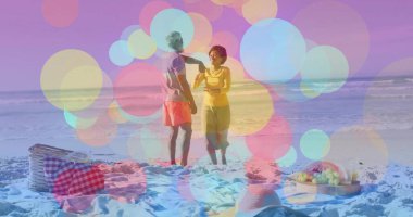 Plajda günlük giysiler giymiş piknik sepeti ve meyve tepsisiyle konuşan ve içecek tutan çiftler. Romantik, boş zaman, açık hava, doğa, rahatlama, mutluluk, canlı