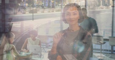 Gözlüklü bir kadın ve kafe penceresinin yanında duran bir ekip dizüstü bilgisayarla iş birliği yapıyor. İşbirliği, takım çalışması, modern, parlak, gündelik, çalışma alanı, iletişim