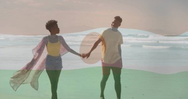 Okyanus kıyısında el ele tutuşan, güneş gözlüklü ve pembe tozlu yürüyen bir çift. Romantizm, eğlence, sahil, rahatlama, açık hava, kaygısız, canlı