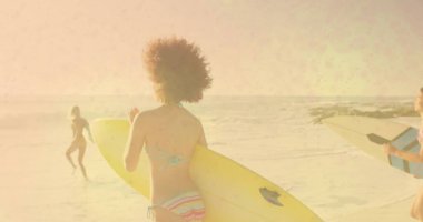 Üç tane mayo giymiş sörfçü ıslak kumda okyanusa doğru sarı, beyaz-mavi sörf tahtaları taşıyor. Macera, açık hava, enerjik, fitness, boş zaman, kıyı, aktivite