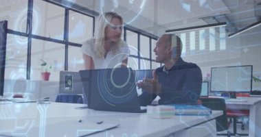 Kadın iş arkadaşının arkasında yürüyor ve erkek iş planı verilerini yönetirken grafik simgesini işaret ediyor. İşbirliği, takım çalışması, yenilik, modernlik, profesyonel, iletişim, veri analizi