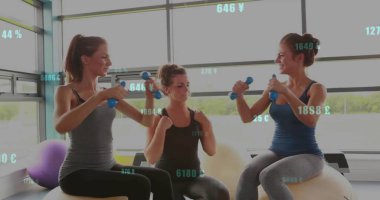 Spor salonunda üç kadın halterleri kaldırıyor. Büyük camları ve para birimi kaplamaları var. Fitness, takım çalışması, dinamik, sağlık, modern, canlılık, eğitim