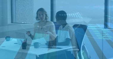 İki iş kadını ofiste dizüstü bilgisayar ve kahve fincanlarıyla oturmuş belgeleri tartışıyor. İşbirliği, takım çalışması, profesyonellik, işyeri, modernlik, üretkenlik, iletişim