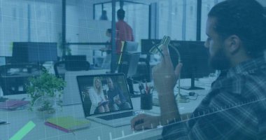 Ekose tişörtlü, sakallı bir adam ofiste bilgisayarlı meslektaşlarıyla iş birliği yapıyor. İşbirliği, takım çalışması, modernlik, dijital iletişim, teknoloji, üretkenlik, çalışma alanı