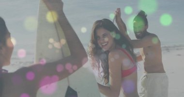 Mayo giyen üç arkadaş, açık gökyüzünün altında kumlu kıyı şeridinde sörf tahtası tutuyor. Sahil, deniz kenarı, tatil, boş zaman, açık hava, macera, canlı