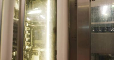 Damla kaplı cam paneller, parmaklıklar, korkuluklar ve floresan tüplerle çevrili odaları gösteriyor. Sanayi, makine, otomasyon, imalat, teknoloji, hassasiyet, mekanik