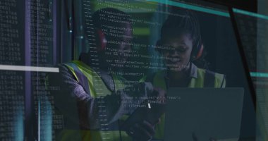 Güvenlik yelekleri giyen iş arkadaşları teknoloji odasındaki cam panelin arkasındaki dizüstü bilgisayarı analiz ediyorlar. Teknoloji, takım çalışması, işbirliği, yenilik, dijital, profesyonel, fütürist