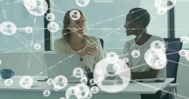 Bluz giyen bayan meslektaşlar ofiste bilgisayar ve kahve fincanıyla ağ kaplamasını tartışıyor. İşbirliği, takım çalışması, modern, profesyonel, teknoloji, iş dünyası, iletişim