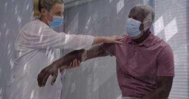 Hasta bakıcı ve hasta muayene odasında maske laboratuvar önlüğü ve sembollerle kol egzersizi yapıyor. Tıbbi, terapi, klinik, sağlık, rehabilitasyon, teknoloji, sağlık hizmetleri