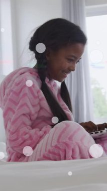 Animation of light spots and trails over african american girl using laptop. Family, free time and digital interface concept digitally generated video.