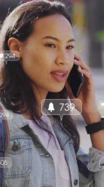 Şehirde akıllı telefon kullanan Asyalı bir kadın hakkında sosyal medya veri işleme animasyonu. Küresel hesaplama, dijital arayüz ve veri işleme kavramı dijital olarak oluşturulmuş video.