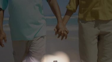 Kıdemli adam ve kadın kıyıda yürüyor, Bokeh haçı başlatıyor inanç için İncil 'le birleştiriyor. Ruhanilik, adanmışlık, dinginlik, inanç, ahenk, tefekkür, saygı