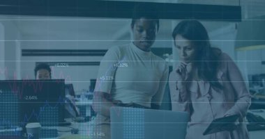 İş kadınları açık planlı ofiste dizüstü bilgisayarı tablet ve finansal tabletlerle inceliyor. İşbirliği, takım çalışması, modernlik, kurumsal, üretkenlik, yenilik, profesyonel