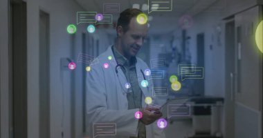 Doctor in lab coat with stethoscope examining smartphone in hospital hall, with chat icons floating. Medical, technology, professional, communication, innovation, healthcare, digital