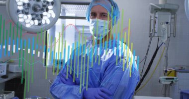 Standing surgeon in scrubs preparing surgery in operating room with surgical lights and data graphs. Medical, healthcare, professionalism, sterile, diagnostic, technology, precision