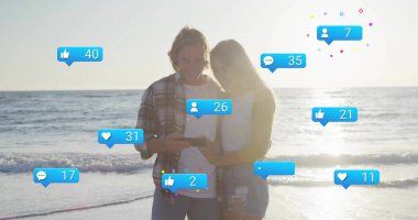 Couple checking smartphone notifications on beach at sunset, with social media icons. Romantic, leisure, reflection, serenity, digital, outdoor, lifestyle