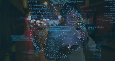 Holding smartphone, European man wearing sweater standing on street at night, with code overlay. Technology, connectivity, cyber, metropolis, innovation, digital, intelligence