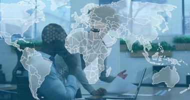 İş arkadaşı raporları inceliyor ve masadaki dizüstü bilgisayarda yazıyor, dünya haritası örtüşüyor, bitkiler. İş, takım çalışması, yenilik, teknoloji, strateji, üretkenlik, modern