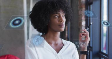 Stylus 'u tutan kadın, ofis penceresinin yakınındaki yüzen holografik panellerle etkileşim halinde. Kopyalama alanı. Teknoloji, yenilik, fütüristik, çalışma alanı, dijital, profesyonel, modern