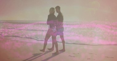 Beyaz kadın ve İspanyol erkek su kenarında kumlu sahil boyunca güneş gözlüğü ve ayak izleriyle yürüyorlar. Romantik, günbatımı, siluet, sahil, rahatlık, sükunet, doğa