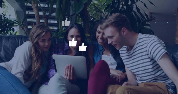 Leaning friends viewing tablet on leather couch in lounge with plants, floating thumbs-up graphics. Conversations, collaboration, relaxation, modern, cozy, social, communication