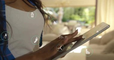 Akıllı evinde tablet kullanan bir kadın yenilenebilir enerji ve yüzen simgelerle karbon ayak izi güncelliyor. Teknoloji, sürdürülebilirlik, dijital, çevre dostu, yenilik, modernite, çevre