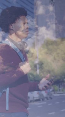 Animation of clouds over african american businessman walking. Global business and digital interface concept digitally generated video.