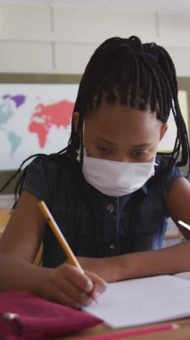 Okul eşyalarının animasyonu, maskeli kız öğrencilerin yüz maskesiyle yazılması üzerine. küresel covid 19 salgın, eğitim ve öğrenme konsepti dijital olarak oluşturulmuş video.