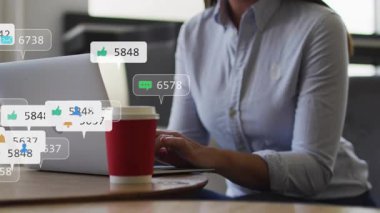 Dizüstü bilgisayarda yazan yetişkin bir kadın sosyal medya artışına işaret eden haber baloncukları üretiyor. Üretkenlik, teknoloji, iletişim, dijital, modern, çalışma alanı, odaklanma