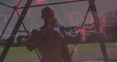 Mavi şişeli, beyaz çitli, metal pavyonun altında üstsüz adam içmek. Atletik, açık hava, hidrasyon, fitness, spor, boş zaman, sağlık