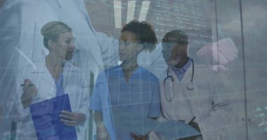 Reviewing digital charts, team in lab coats, scrubs in hospital corridor with clipboard, tablet. Medical, teamwork, collaboration, clinical, diagnostics, professionalism, healthcare