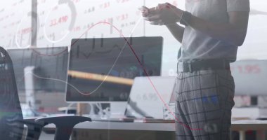 Data analyst wearing gray shirt reviewing charts on monitors in open plan office, copy space. Technology, analytics, finance, workspace, modern, professional, productivity