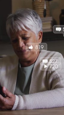 Sosyal medya simgelerinin animasyonu ve akıllı telefon kullanan yaşlı kadın üzerindeki afişler. küresel ağ, sosyal medya, teknoloji ve dijital arayüz kavramı dijital olarak oluşturulmuş vide