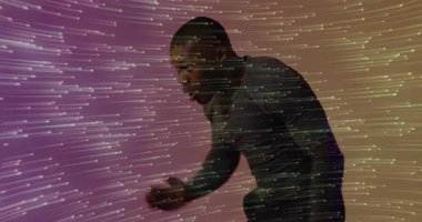 Erkek oyuncu, teknolojiyi göstererek yüzünü koruyor ve yansıtılan ışık çizgilerine yaslanıyor. Dijital sanat, fütüristik, hareket, soyut, dinamik, performans, sürükleyici