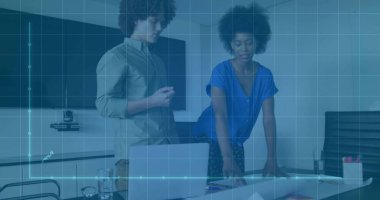 Colleagues wearing business attire reviewing charts and laptop in boardroom, with screen and camera. Professional, collaboration, modern, teamwork, corporate, presentation, analytics