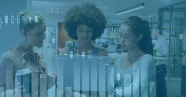 Discussing project, three women standing around laptop in library, with coffee cup and bookshelves. Collaboration, teamwork, innovation, workspace, modern, education, technology