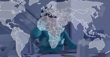 Worker wearing VR headset navigating digital world map at office desk, laptop documents smartphone. Technology, innovation, futuristic, digital, business, virtual, workspace