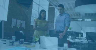 Viewing laptop screen, office colleagues collaborating at open plan office, with notebooks, plants. Professional, teamwork, collaboration, workspace, modern, productivity, corporate