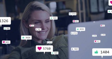 Zeytin yeşili tişörtlü gülümseyen yaratıcı yüzen sosyal simgelerle masada dizüstü bilgisayarı izliyor, kopyalama alanı. Dijital pazarlama, içerik oluşturma, üretkenlik, canlı, modern, takım çalışması, iletişim