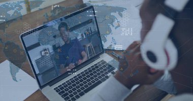 Displaying laptop hosting meeting at wooden desk with world map, over-ear headphones, paper sheet. Collaboration, remotework, technology, communication, professional, connectivity, modern